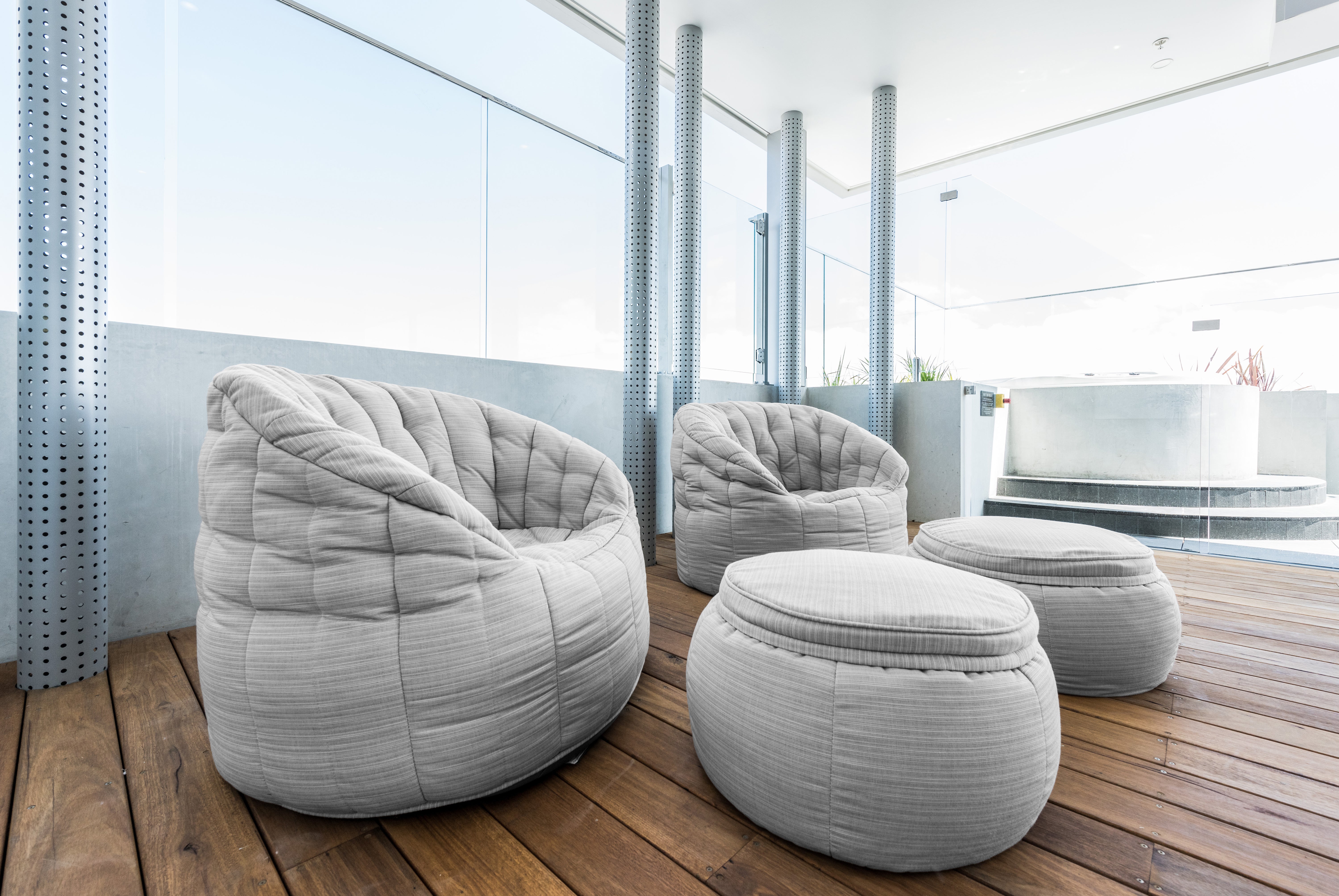 Grey Butterfly Sofa and Wing Ottoman bean bag chaise lounges on the wooden deck of a rooftop lounge.