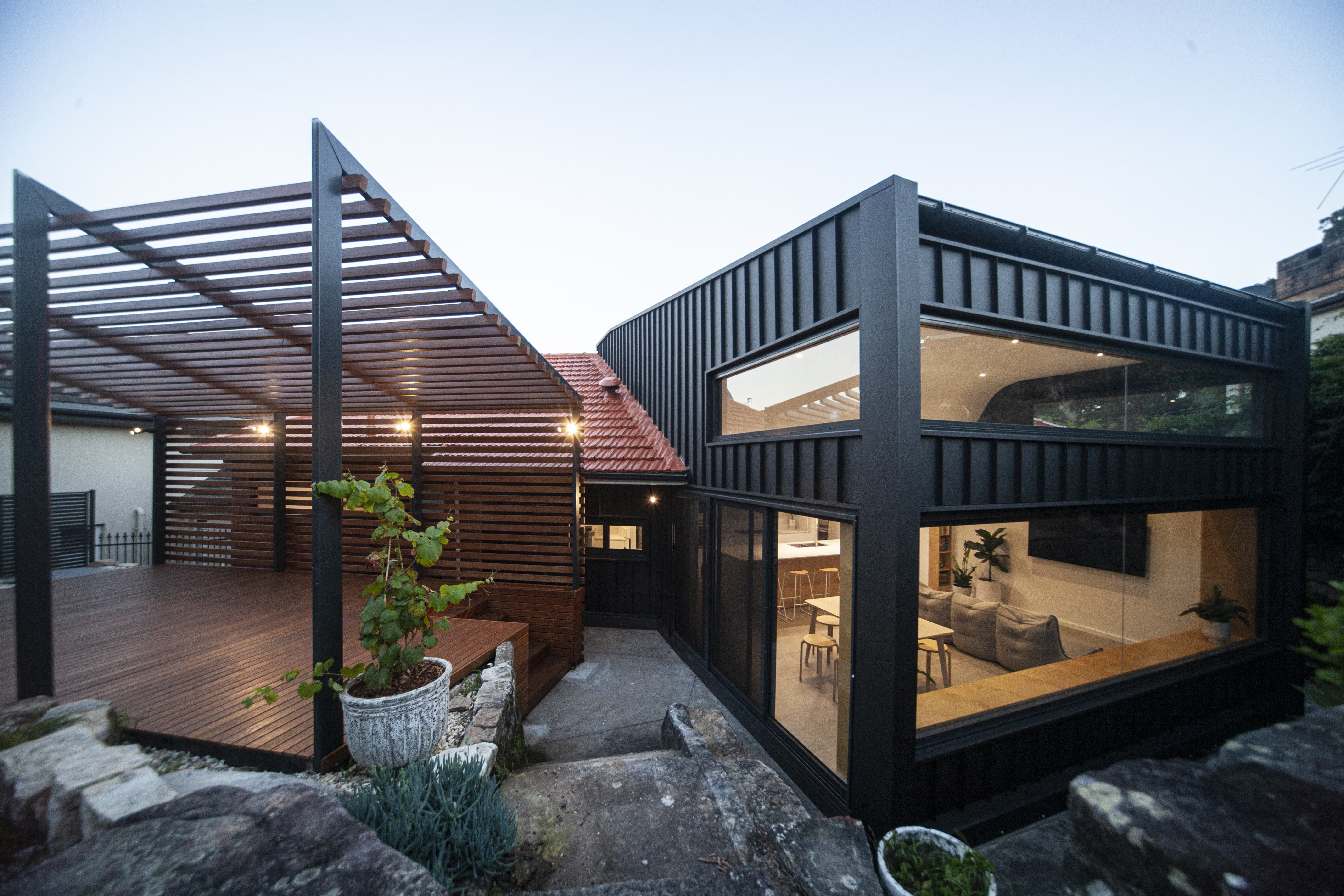 External view of outdoor terrace and block with open-plan living, dining and kitchen space.