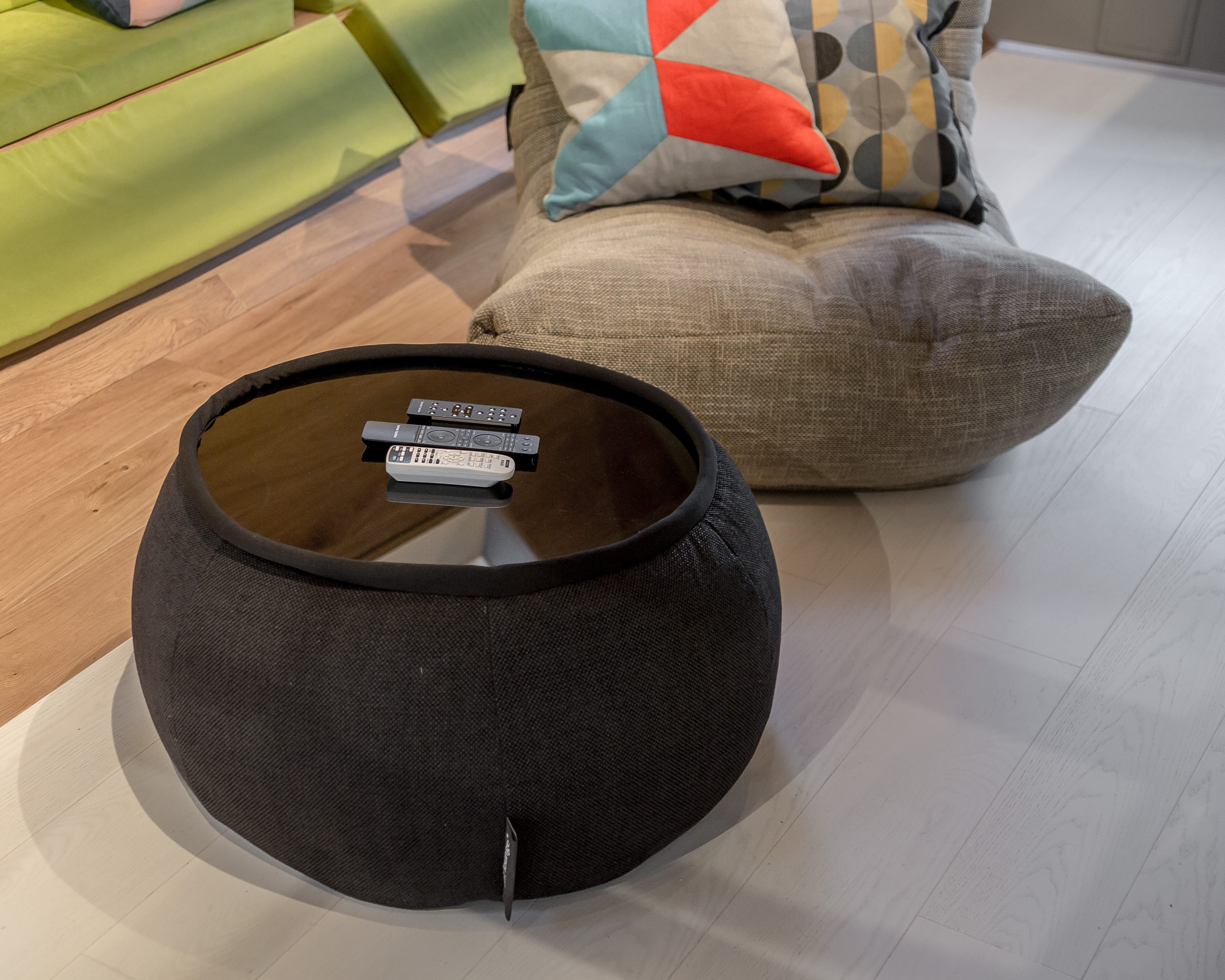 Black Versa Table bean bag with remote controls on the tabletop in a modern attic with a light wood floor.